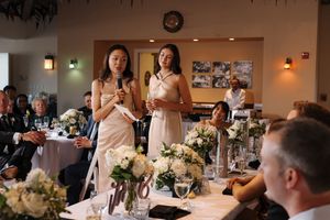 Wedding reception guests enjoy a candlelit dinner in an elegant banquet hall with white floral centerpieces.