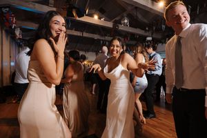 A group dances and celebrates together at an indoor wedding reception with warm lighting.