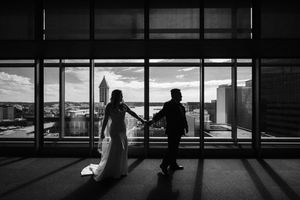 A series of silhouettes stand against large windows in an airport terminal with dramatic lighting and shadows.