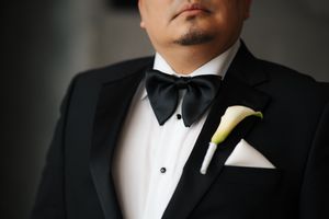 Close-up details of a formal black tuxedo with white dress shirt and bowtie for a wedding or special occasion.