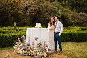 Romantic outdoor wedding setup with floral decorations and rustic furniture in a lush garden setting.