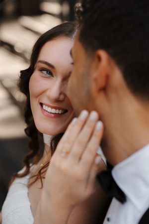 A close-up romantic wedding portrait showing a tender moment between newlyweds in natural lighting.