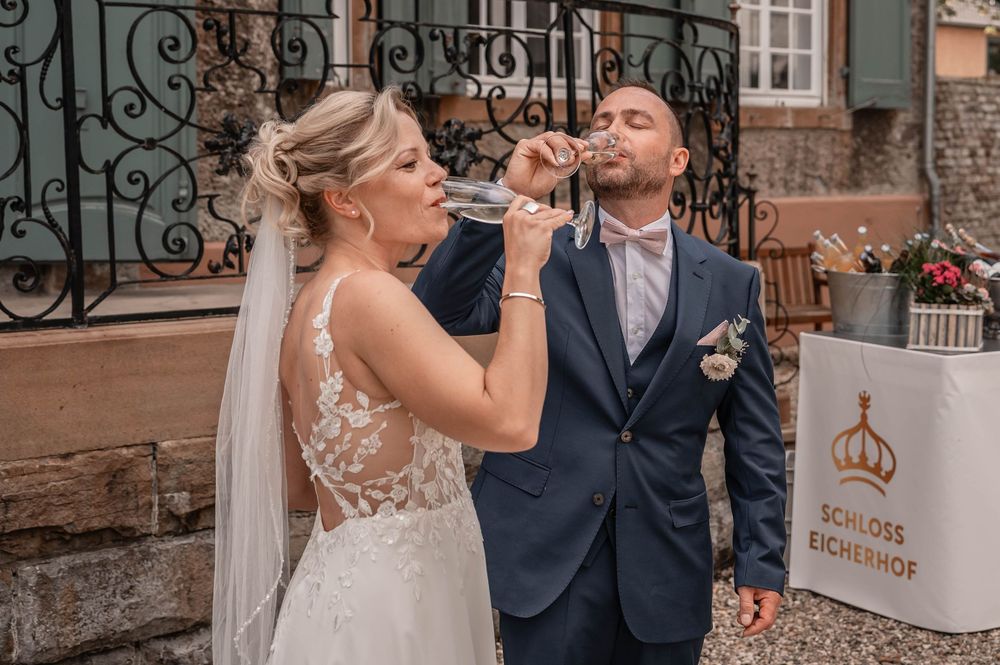 Bride and groom share a romantic moment in front of an ornate iron gate and brick building exterior.