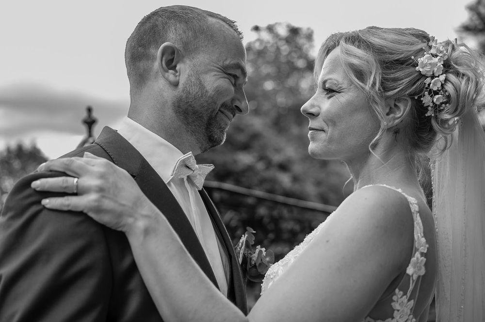 A black and white candid wedding photo showing a joyful moment between newlyweds on their special day.