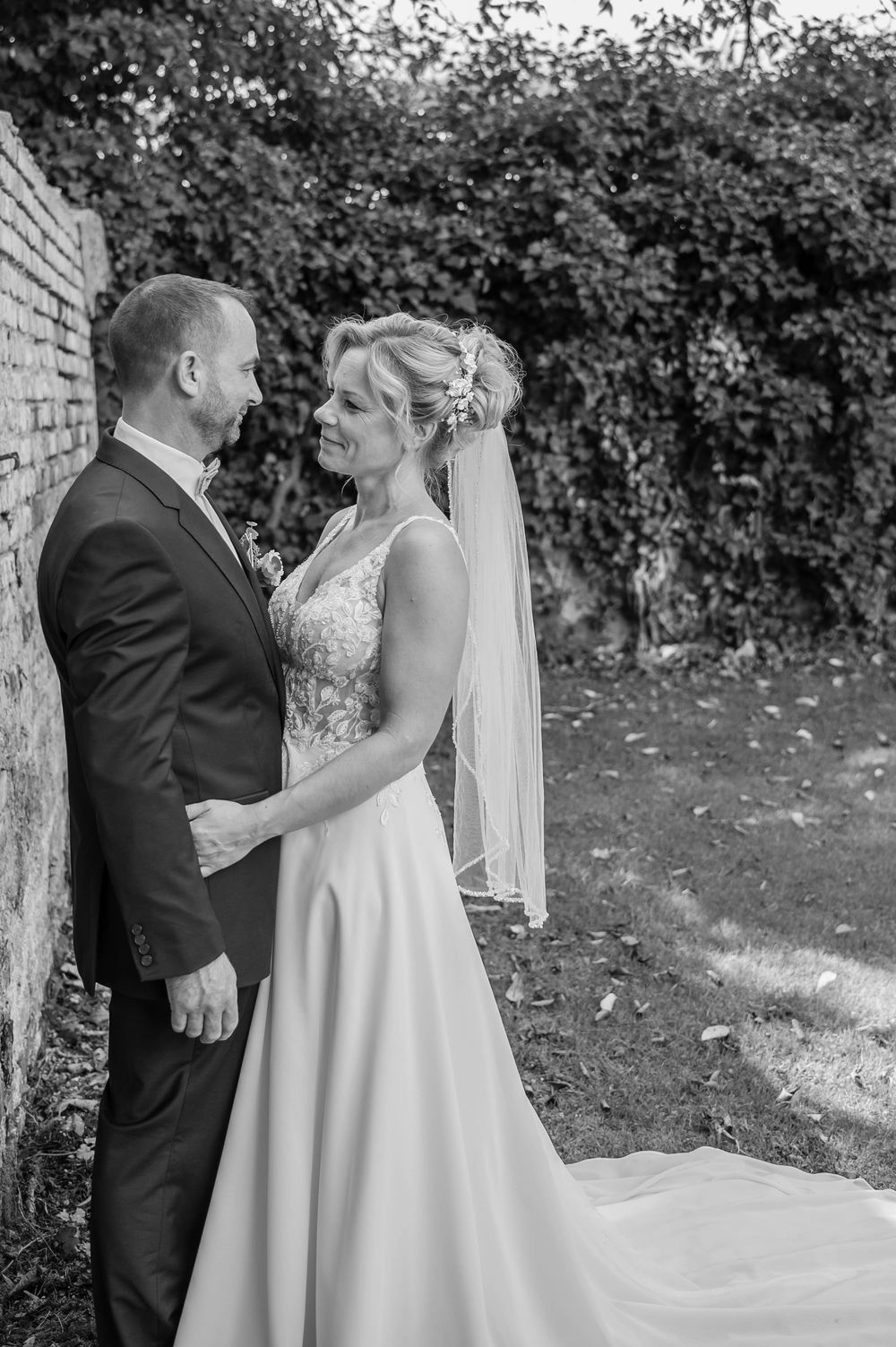 A romantic black and white wedding photo series showing a couple sharing tender moments under a garden archway.