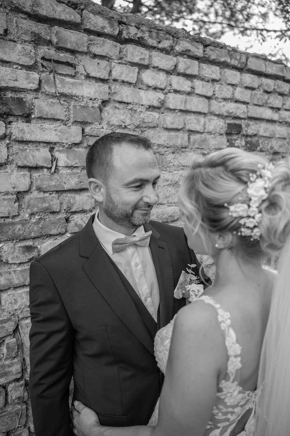 A romantic black and white photo sequence showing a couple in wedding attire against a brick wall.