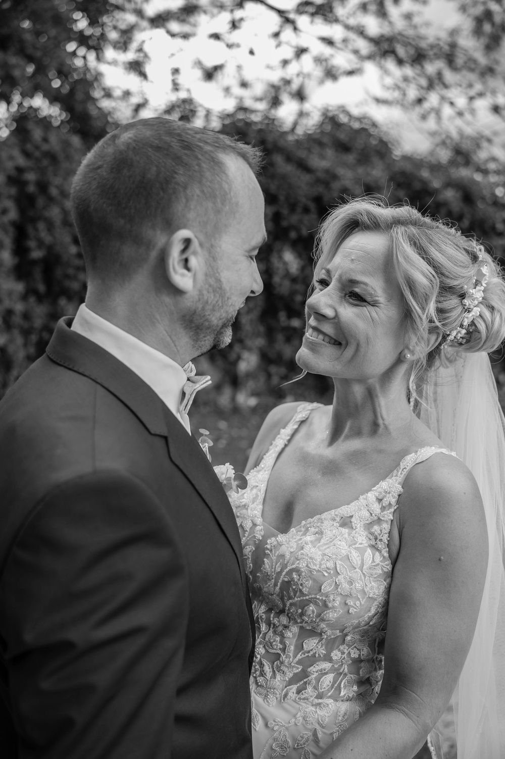 Black and white wedding photos show a joyful couple sharing intimate laughing moments together outdoors.
