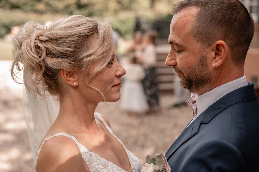A romantic moment between a couple in formal wedding attire as they embrace outdoors.