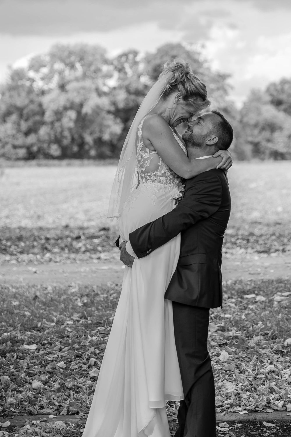 Black and white sequence of a romantic wedding couple embracing and kissing in an autumn field with fallen leaves.