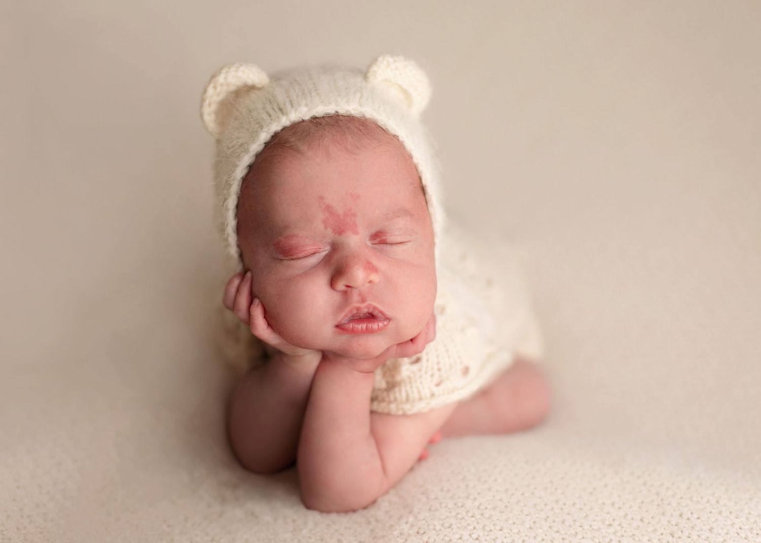 A collection of artistic newborn photos featuring a baby wearing a white knit bear hat on cream background.