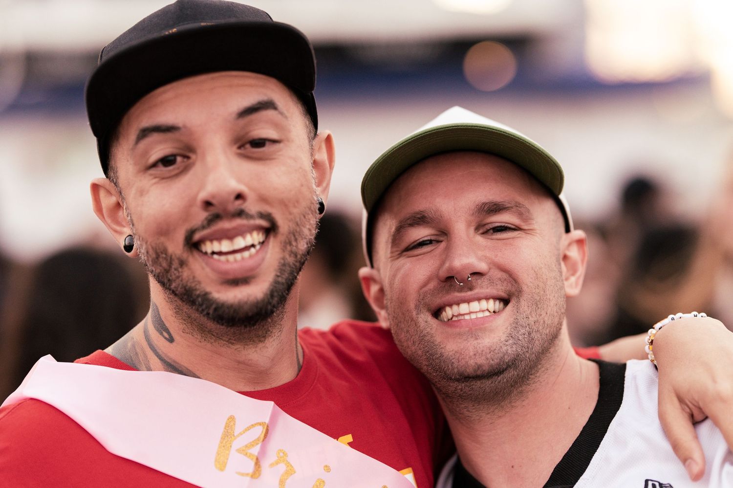 Two sports fans smile together while celebrating at an outdoor event.