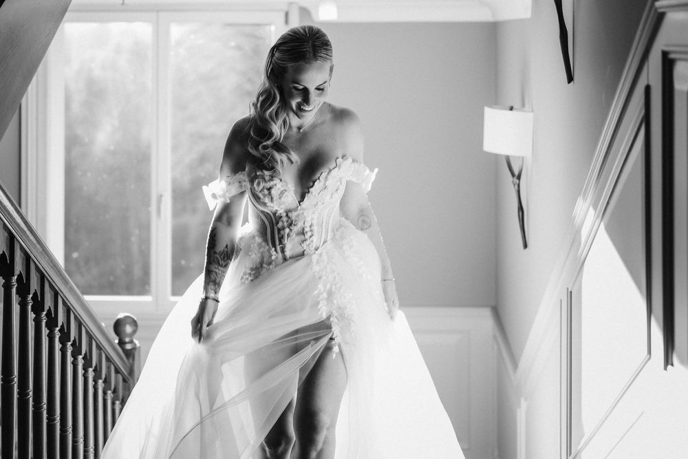 Black and white photo of delicate lace details on a wedding gown in natural window light.