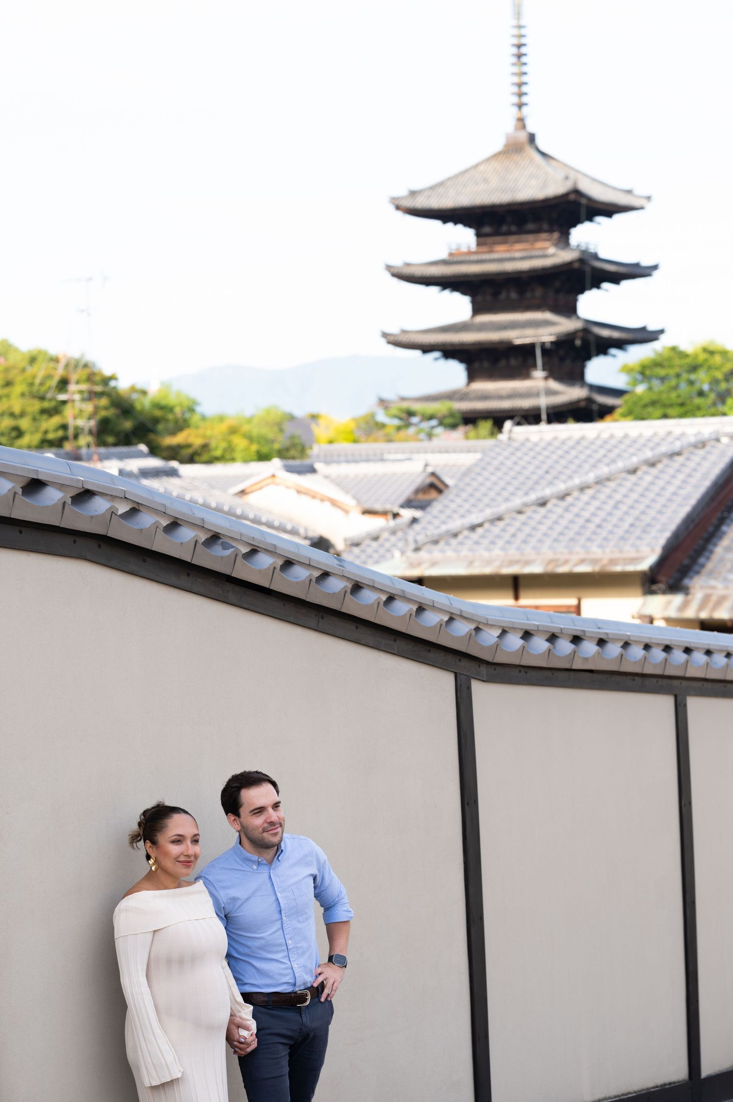 Couple stands together with a historic Japanese five-story pagoda rising in the background.