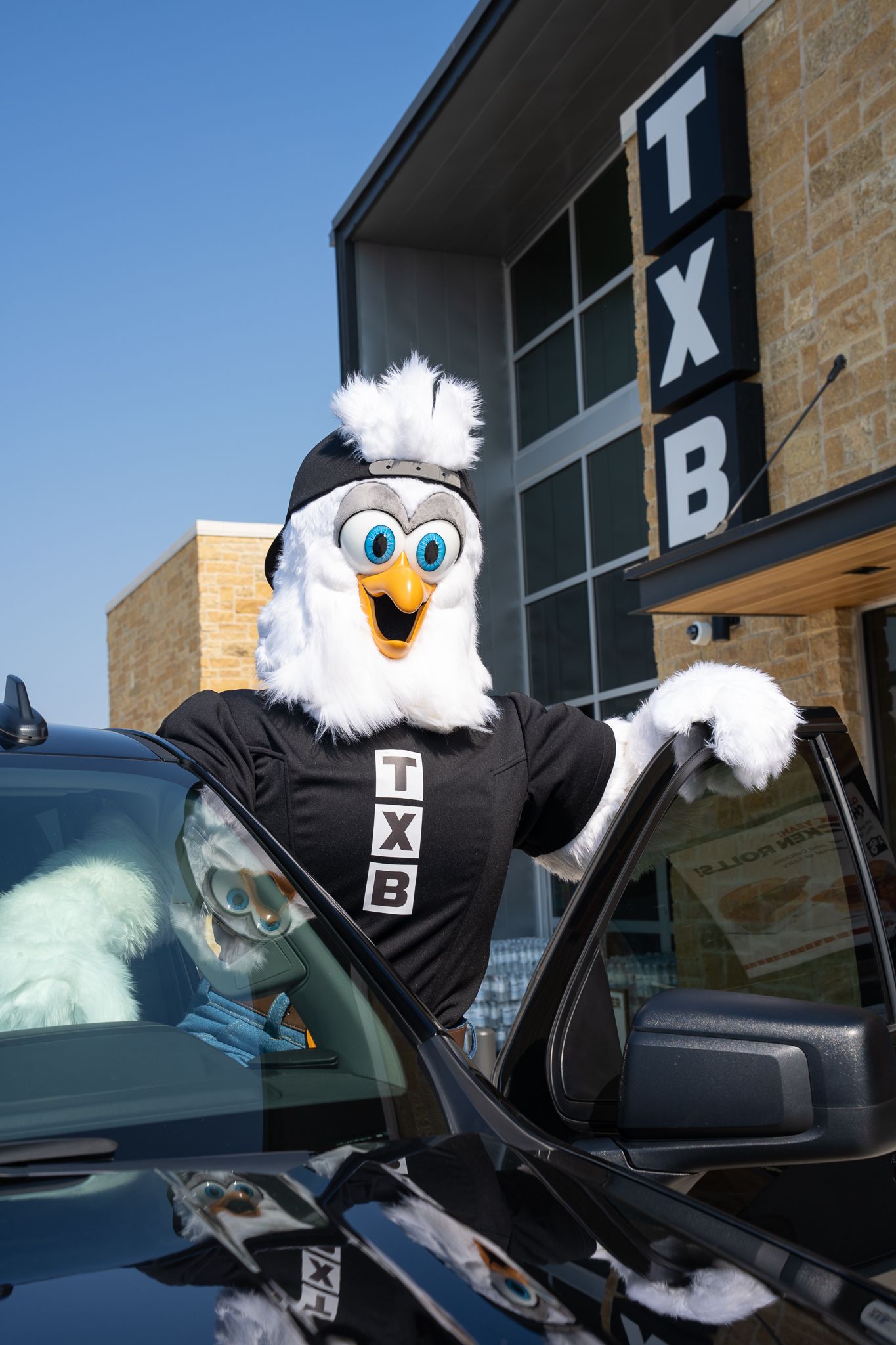 A white mascot character in a black outfit entering a car in a series of sequential photos.