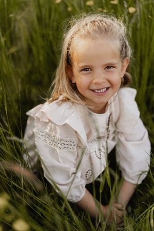 A candid series of photos shows someone in a white vintage-style dress playing joyfully among tall grass.