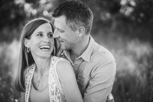 A couple shares a joyful moment together outdoors in black and white portrait photography.
