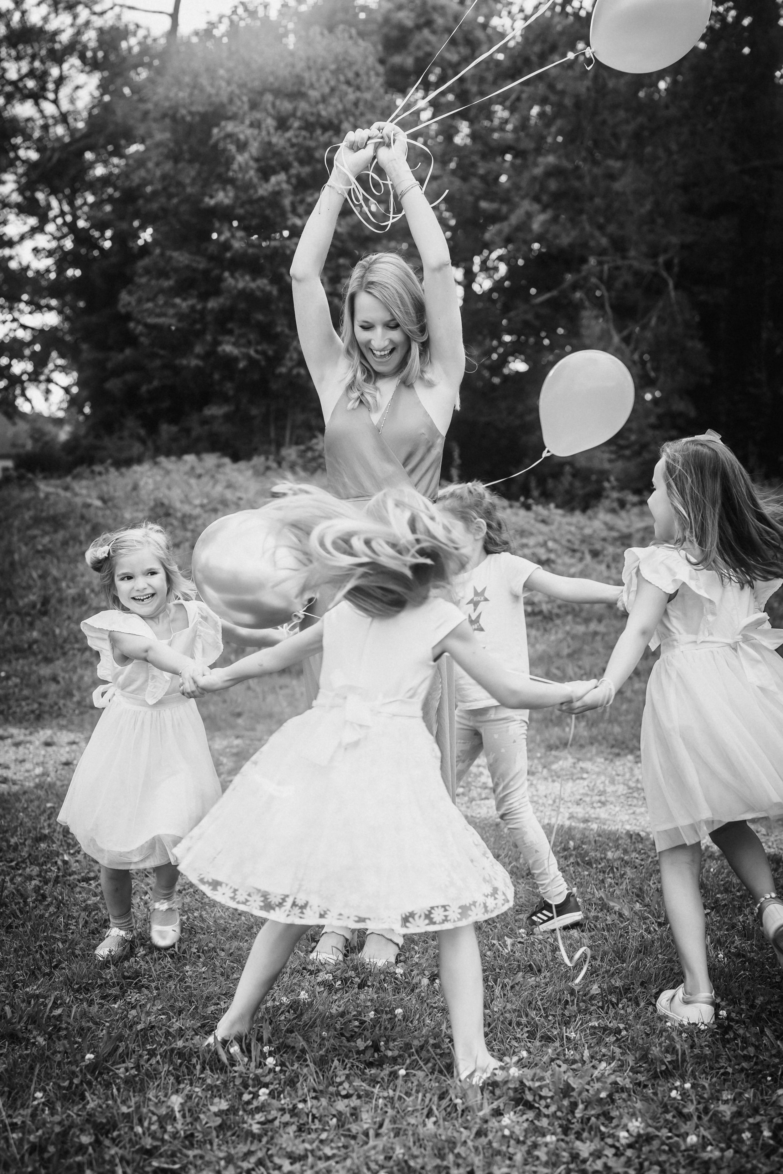 Black and white photo series showing children in white dresses playing with balloons outdoors in a dreamy sequence.
