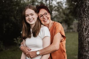 Two happy people in an outdoor setting wearing orange and white outfits embracing and laughing together.