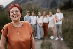 A group poses together on a mountain trail with someone in an orange sweater standing in the foreground.
