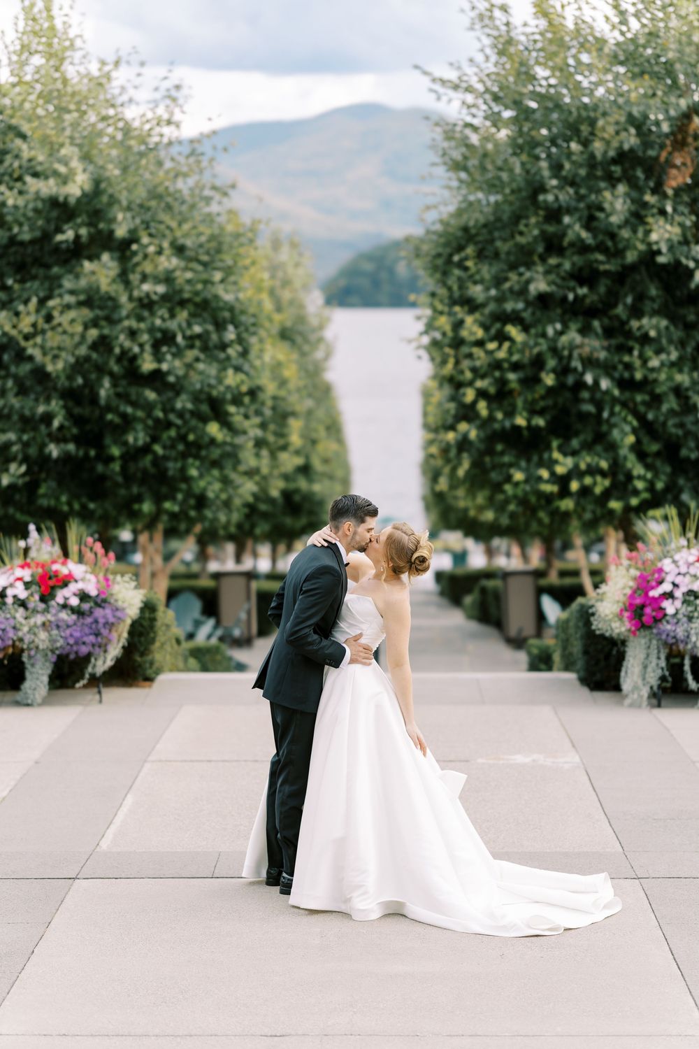 A romantic outdoor wedding photo sequence at a scenic lakeside venue with trees and flowers.