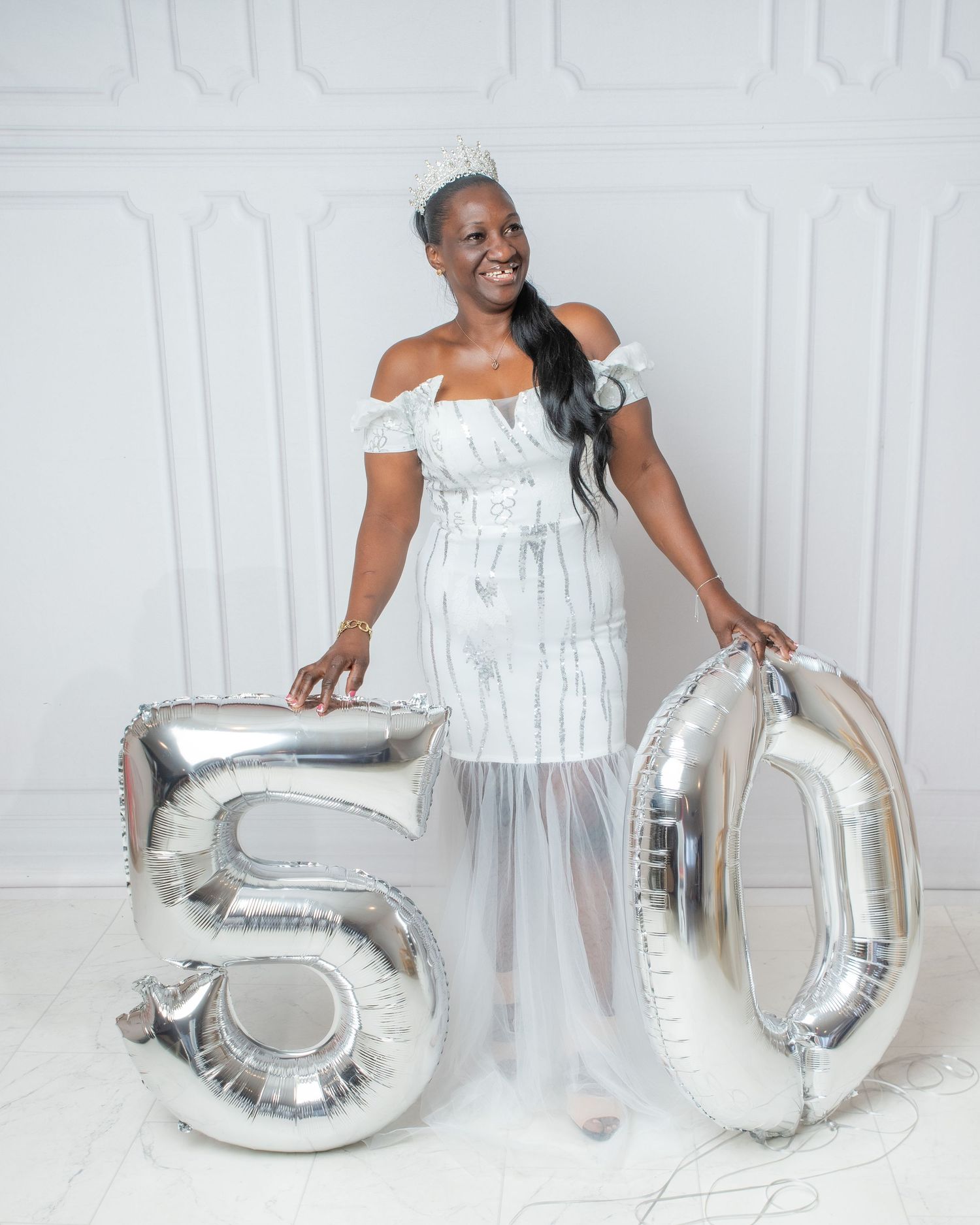 A sequence of photos showing a person in a white outfit sitting and posing with silver number balloons in a studio setting.