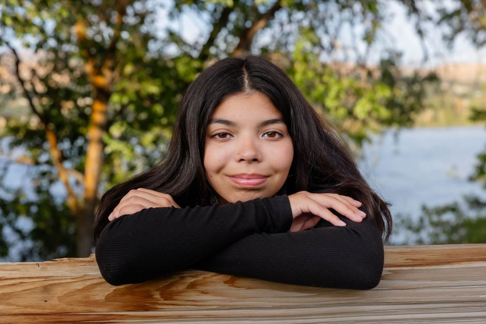 Person resting arms on wooden surface in outdoor setting.