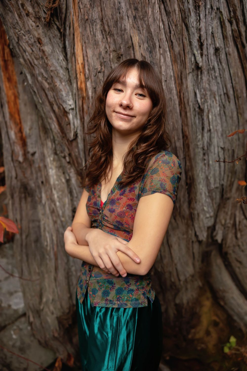Casual portrait session against a weathered tree trunk wearing a patterned top and teal skirt.