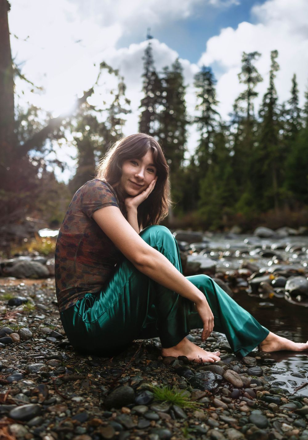 Artistic outdoor photography on a rocky beach with evergreen trees and cloudy skies in the background.