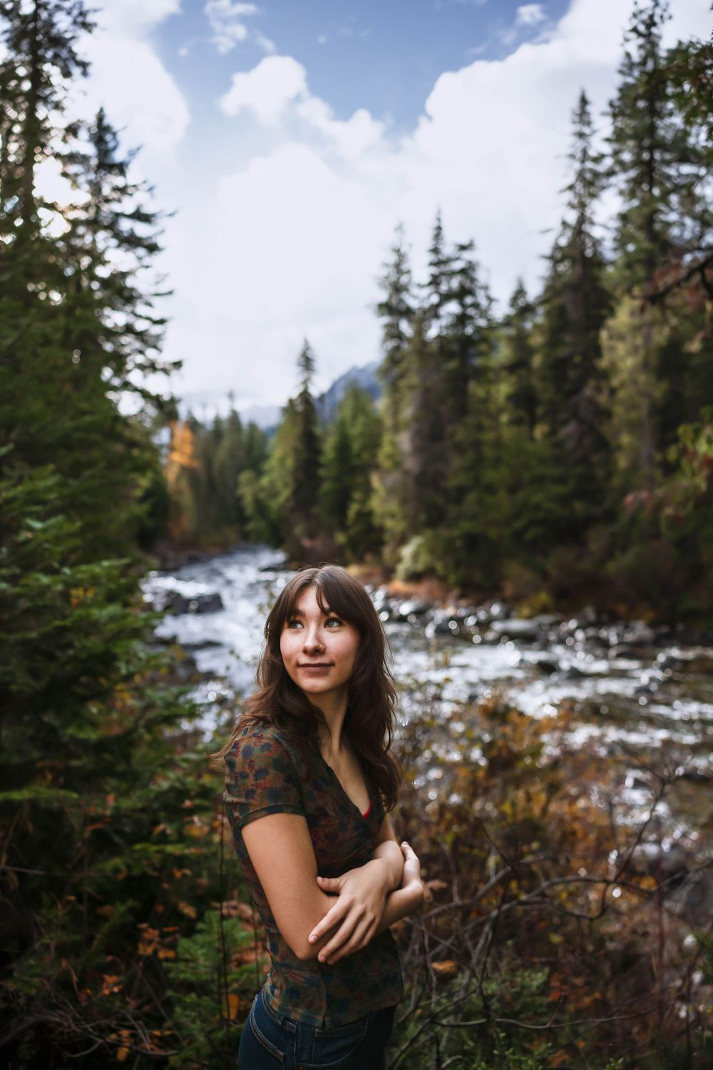 Natural outdoor portrait with evergreen trees and snowy mountains creating a scenic backdrop.