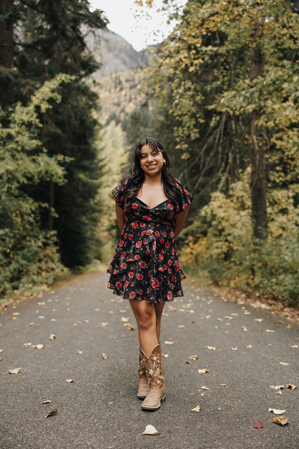 Person in a red floral dress walks along an autumn forest path.