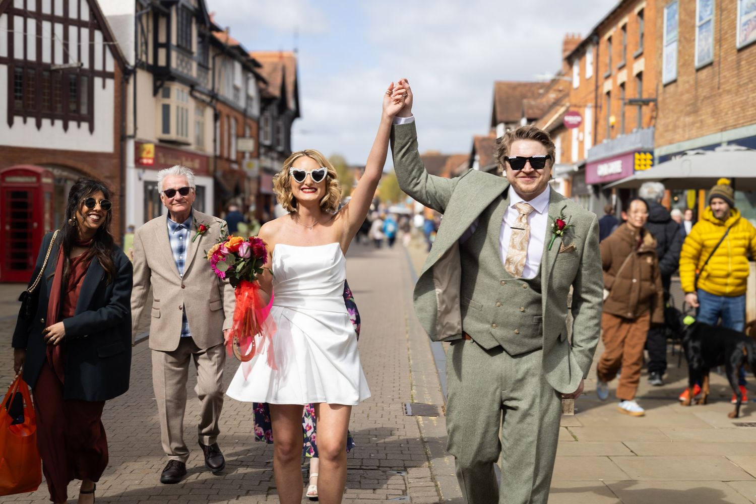 Wedding party members in formal attire having conversations as they walk together in a sunny outdoor venue.