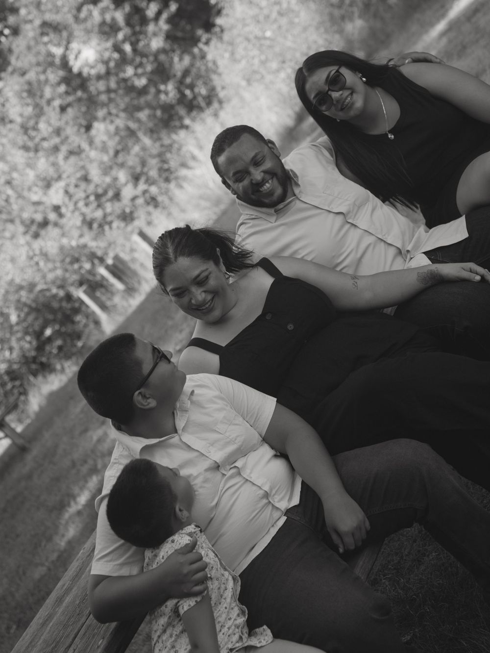 A group lounges together outdoors in a casual black and white photo.