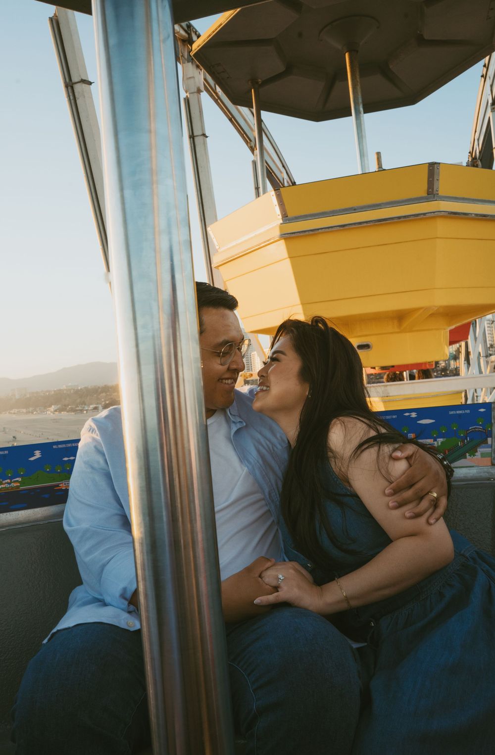 Couple sharing a romantic moment on a Ferris wheel at Santa Monica Pier on a sunny day.