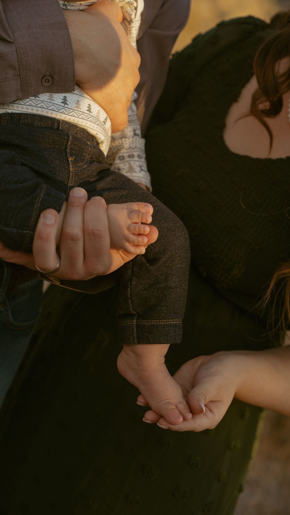 Close-up shot of hands tenderly holding each other in natural lighting.