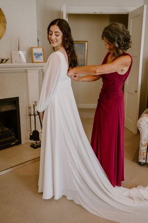 Wedding dress fitting scene showing elegant white gown with flowing train and burgundy bridesmaid dress. christchurch wedding photography