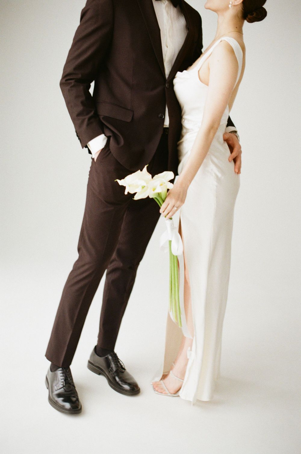 Modern wedding photography showing bride in white dress and groom in dark suit captured from knee level in minimalist style.