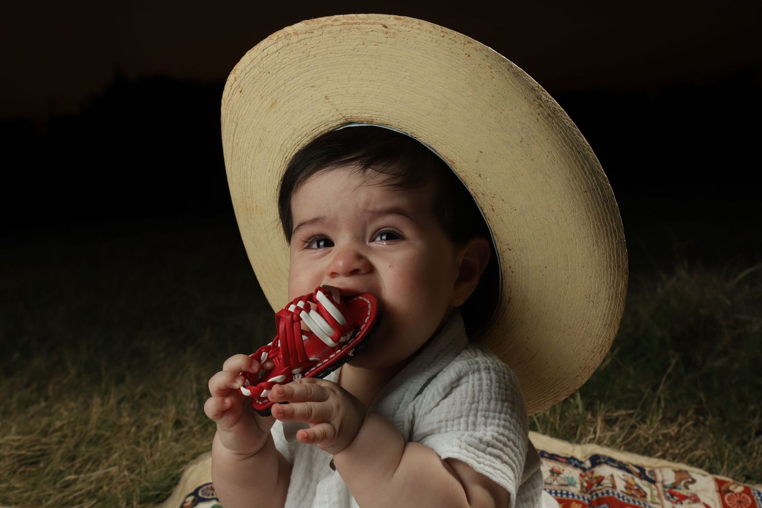A toddler in a cowboy hat enjoys a juicy slice of watermelon during a summer day outdoors.