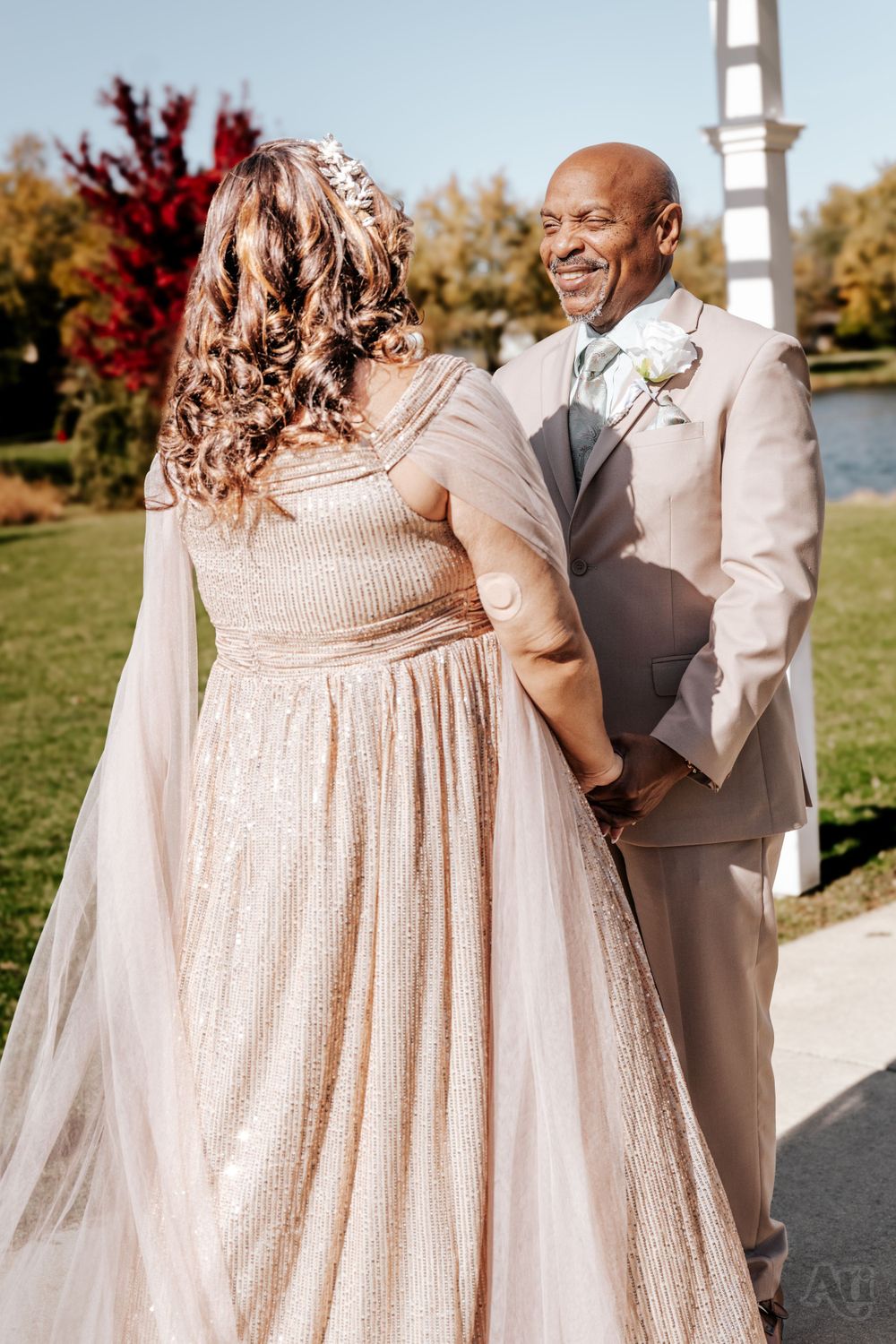 A joyful outdoor wedding ceremony with the couple wearing champagne colored attire on a beautiful autumn day.