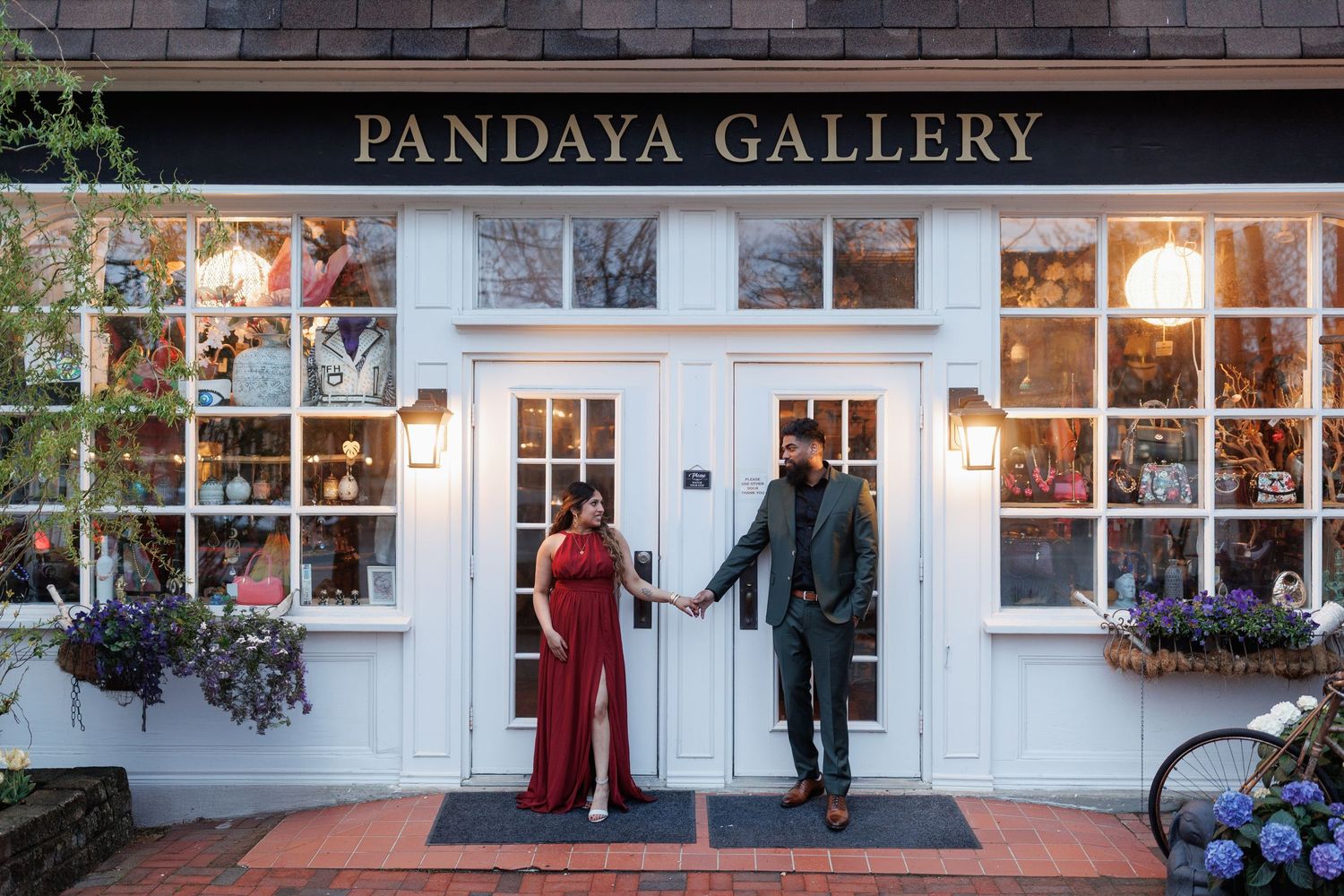 Couple in formal attire standing outside Pandaya Gallery storefront at dusk.