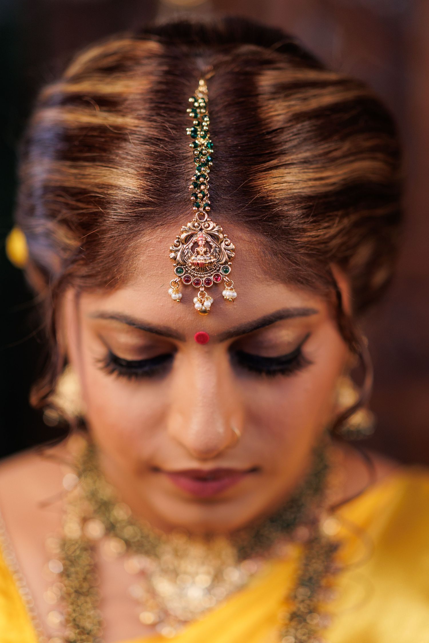 Close-up of traditional South Asian bridal jewelry and makeup details.