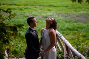 Bride laughs joyfully while holding hands with bride during outdoor wedding portrait session.