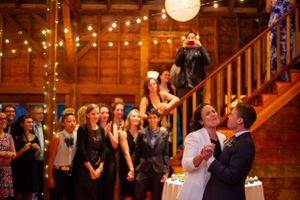 Couple shares first dance as wedding guests watch inside warmly lit rustic barn venue.