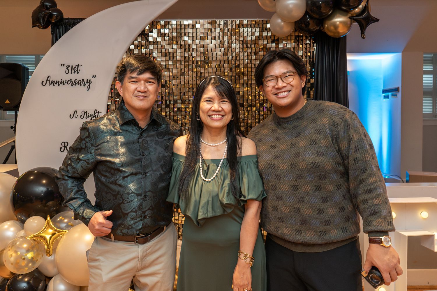 A group of people celebrating at a festive gathering with sparkling lights and decorations in the background.