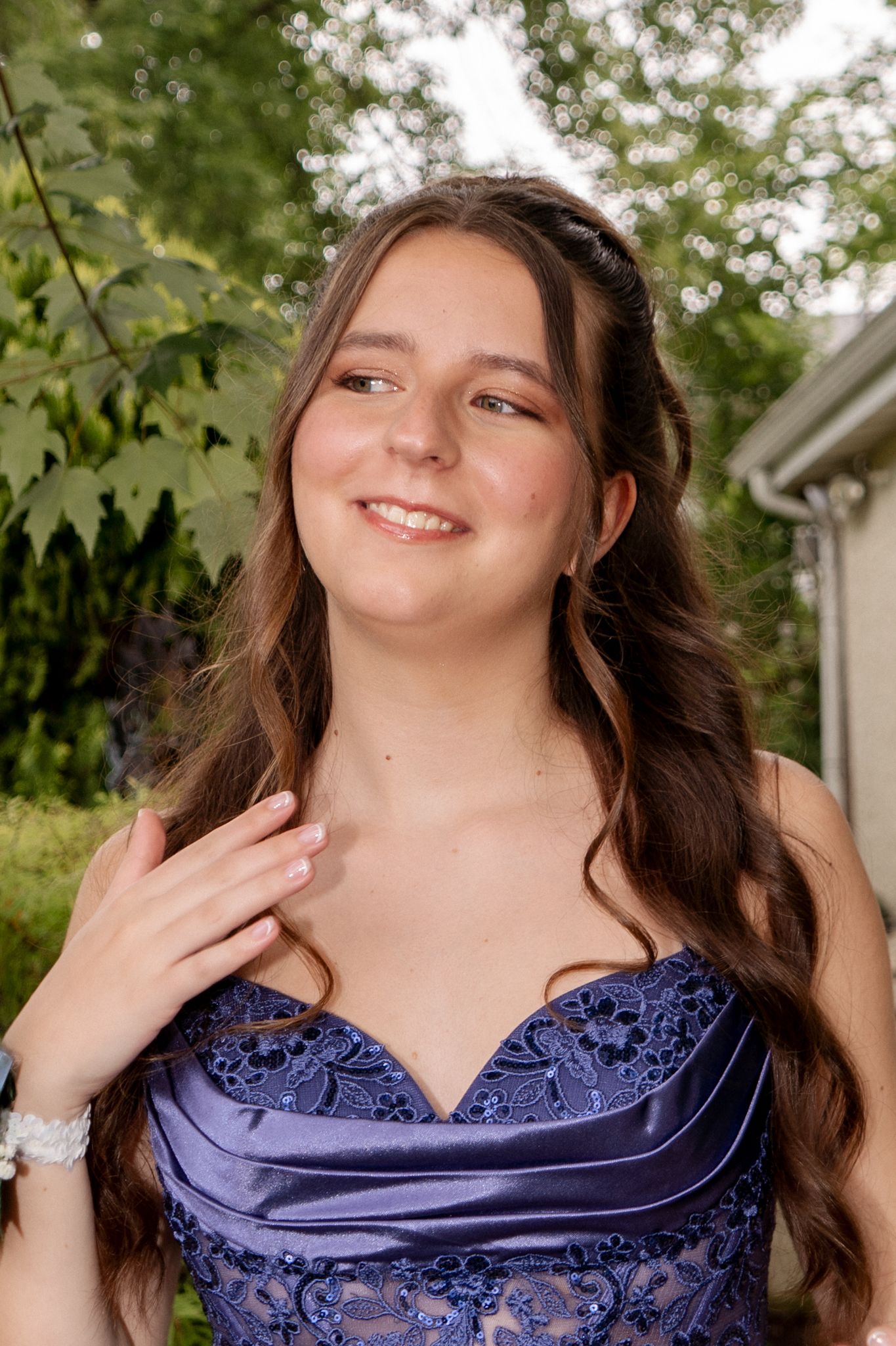 Person in a navy blue formal dress posing outdoors with trees in background.