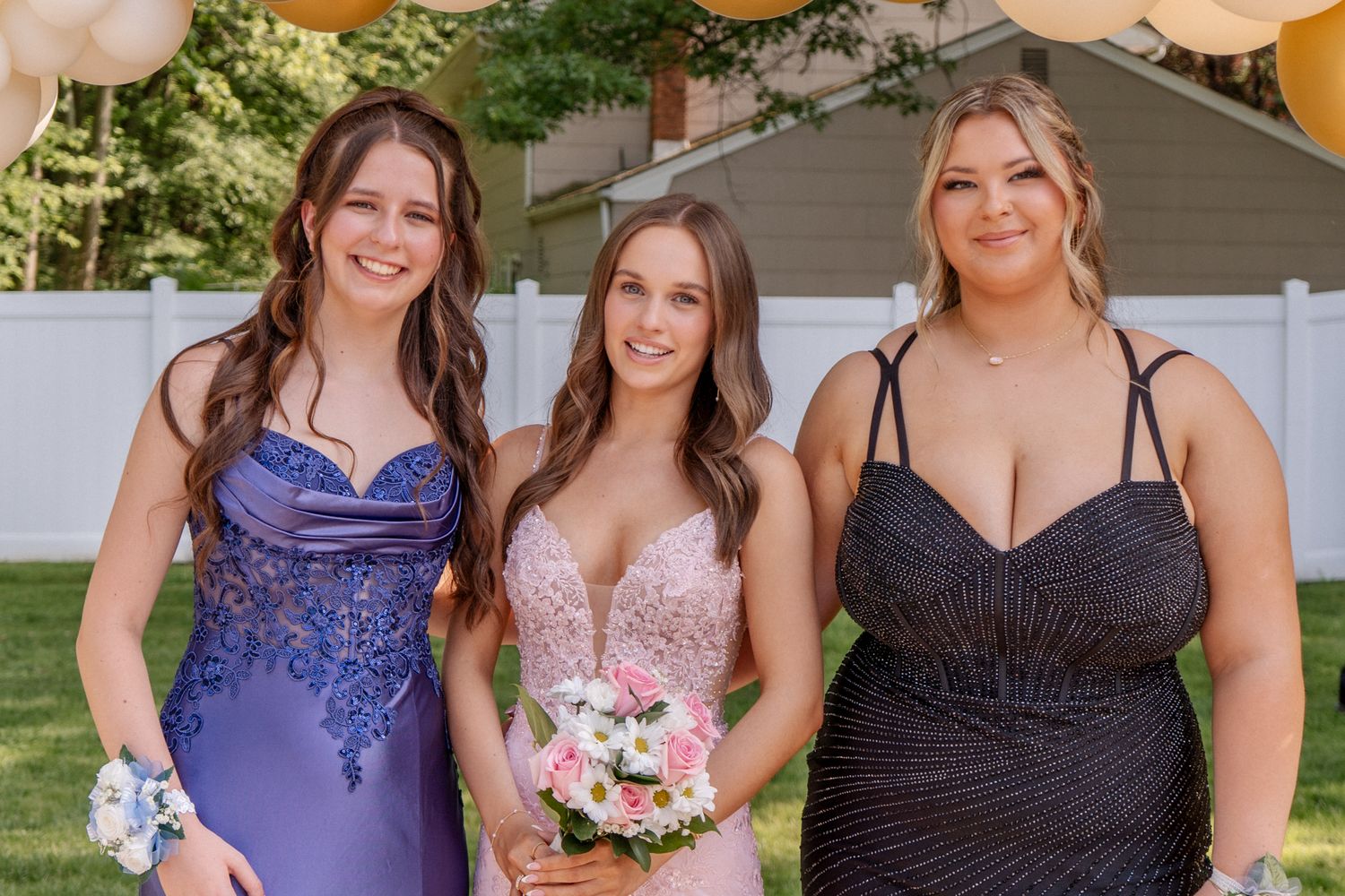 Row of people in formal attire holding bouquets at an outdoor event.