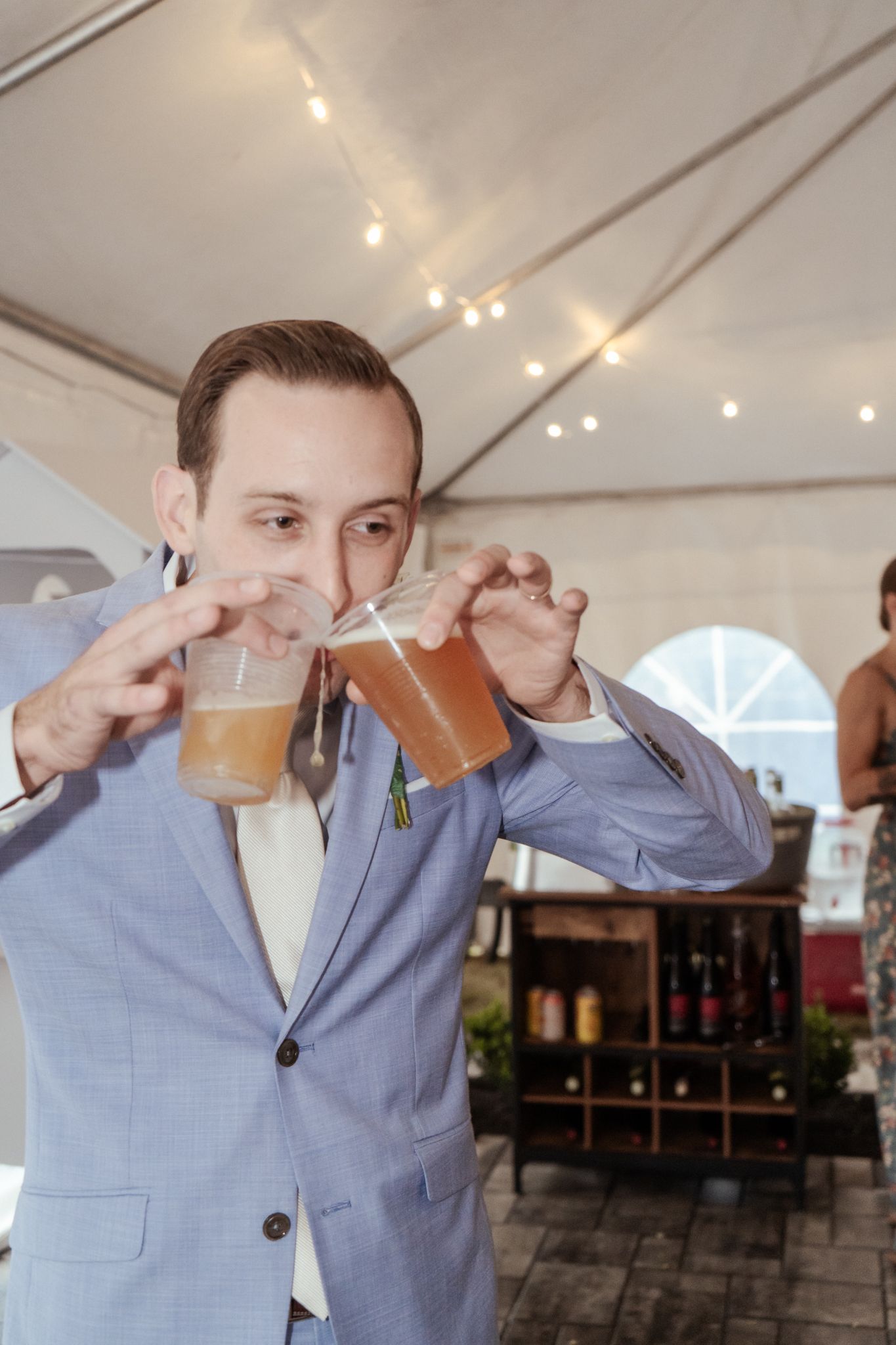 A person in a light blue suit takes multiple sips from a drink in sequence.