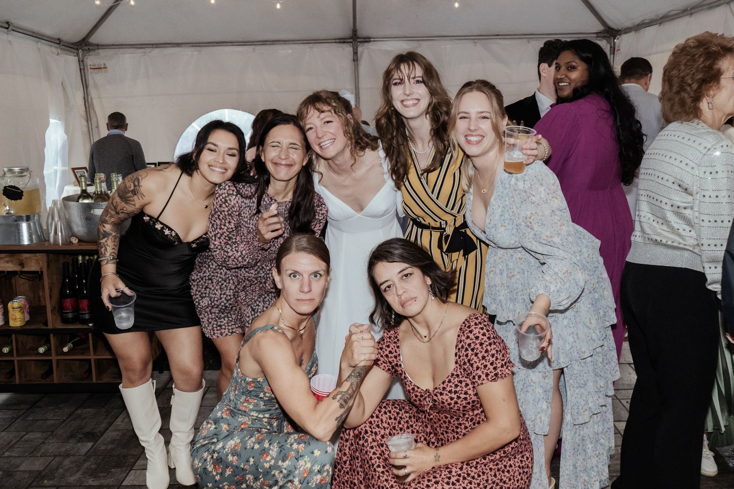 Wedding party members embrace and laugh together during reception celebrations.