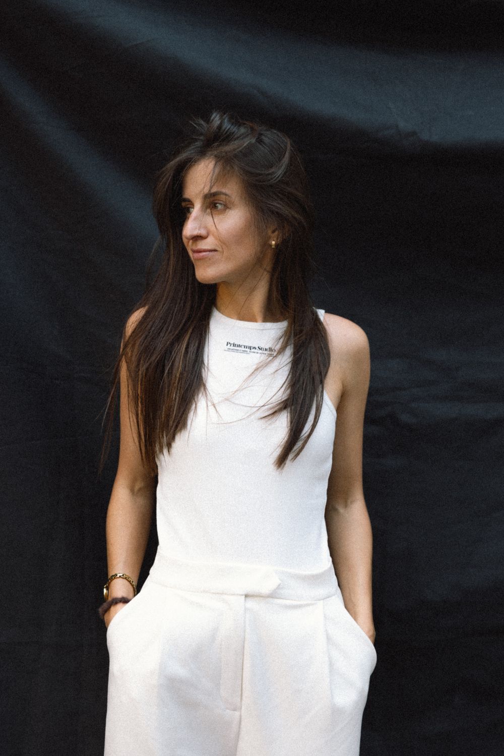 Person wearing a sleeveless white dress with pockets poses against dark background in multiple angles.