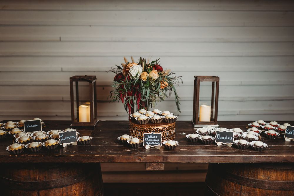 Rustic dessert table with lanterns and floral centerpiece at wedding reception.