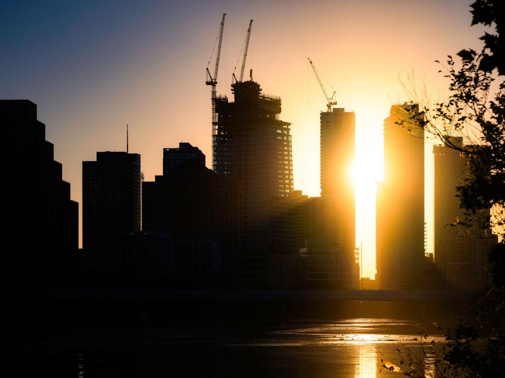 Dramatic silhouette of Austin city skyline during golden sunset with sun peeking between buildings.